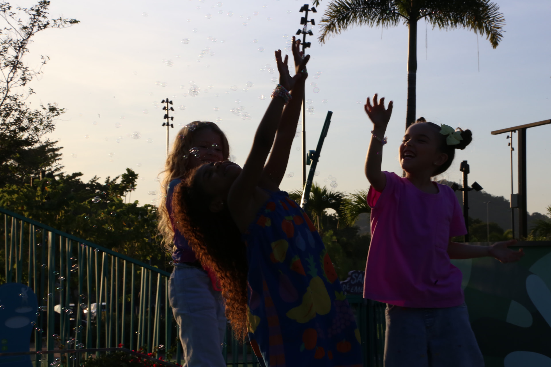 Crianças brincando com bolhas de sabão ao ar livre no fim da tarde